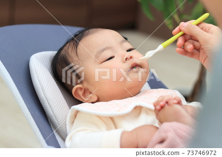 Baby feeding baby food in the living room 73746972