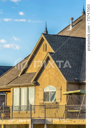 Close up exterior of a house with brown wall and dark roof against blue sky Close up exterior of a house with brown wall and dark roof against blue sky 73747003