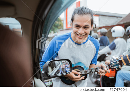 a busker approaches a car window when traffic is jammed a busker approaches a car window when traffic is jammed 73747004