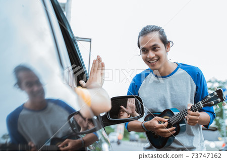 busker using a musical instrument and singing was rejected by someone from the car 73747162