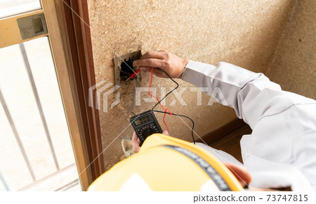 Residential remodeling site A businessman investigating the energization of an AC outlet 73747815