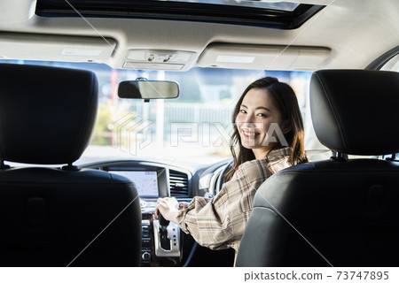 A young woman driving a car 73747895