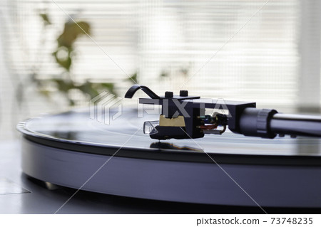 Listen to music on a record player by the window where the sun shines 73748235