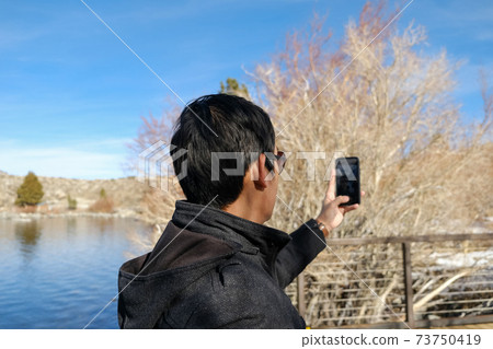 travel man use smart phone o taking photo of the beautiful mountain landscape. travel man use smart phone o taking photo of the beautiful mountain landscape. 73750419