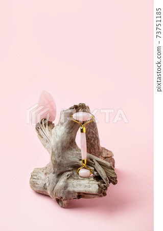 Jade roller for face massage. Pink gua sha facial massager tools on wooden root. Anti age, lifting and toning treatment, monochrome beauty banne, copy space, wellness, wellbeing concept Jade roller for face massage. Pink gua sha facial massager tools on wooden root. Anti age, lifting and toning treatment, monochrome beauty banne, copy space, wellness, wellbeing concept 73751185