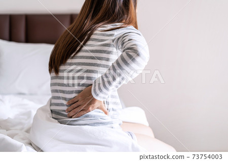 Woman suffering from back ache on the bed in the morning, healthcare and problem concept Woman suffering from back ache on the bed in the morning, healthcare and problem concept 73754003