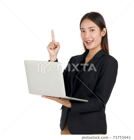 Young asian businesswoman in a black suit holding a laptop computer pointing one finger in upward direction. Portrait on white background with studio light. 73755041