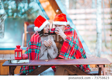 Young family in santa hat sitting on the wooden old table background of their house Young family in santa hat sitting on the wooden old table background of their house 73758623
