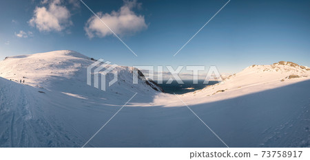 Panorama of snow mountain range with sunshine and blue sky on winter at Lofoten Islands 73758917