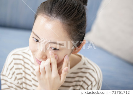 Young woman putting in contact lenses 73761712