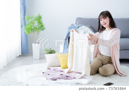 Young women decluttering clothes and changing clothes 73763864