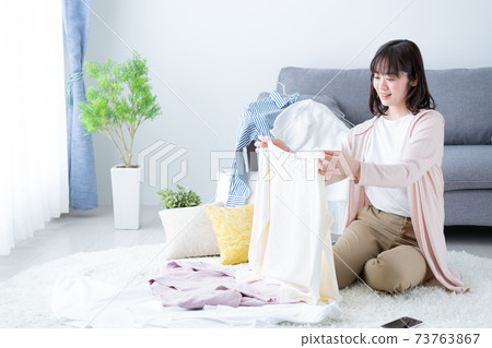 Young women decluttering clothes and changing clothes 73763867