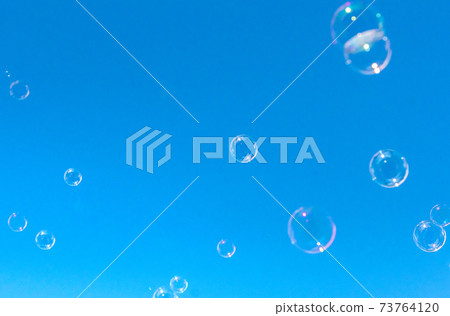 Soap bubbles floating in the blue sky / background material 73764120