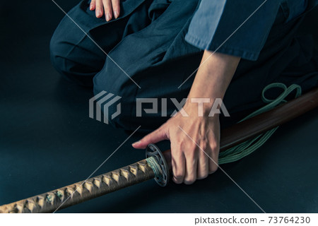 A person sitting upright and a Japanese sword 73764230