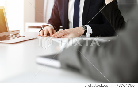 Unknown business people using laptop computer at the desk in modern office. Businessman or male entrepreneur is working with his colleague. Teamwork and partnership concept 73764796