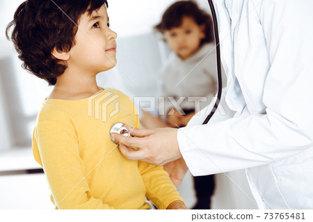 Woman-doctor examining a child patient by stethoscope. Cute arab boy at physician appointment. Medicine help concept 73765481
