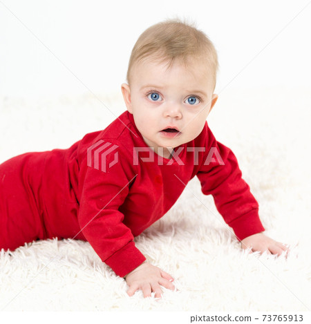 A small child lies on his stomach on a white carpet A small child lies on his stomach on a white carpet 73765913