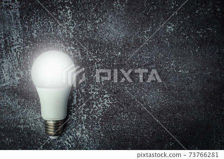 Glowing LED light bulb on dark grunge background 73766281