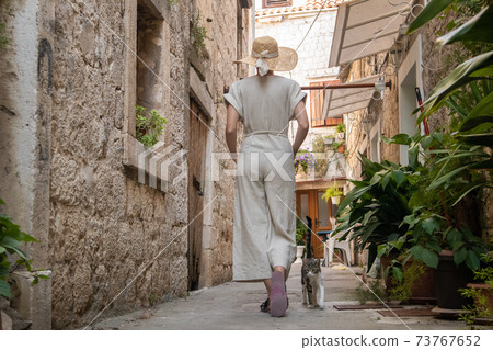 Rear view of beautiful blonde young female traveler wearing straw sun hat sightseeing and enjoying summer vacation in an old traditional costal town at Adriatic cost, Croatia Rear view of beautiful blonde young female traveler wearing straw sun hat sightseeing and enjoying summer vacation in an old traditional costal town at Adriatic cost, Croatia 73767652