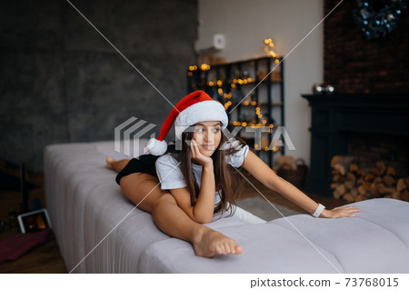 Young woman in santa hat practicing sport gymnastic exercises 73768015