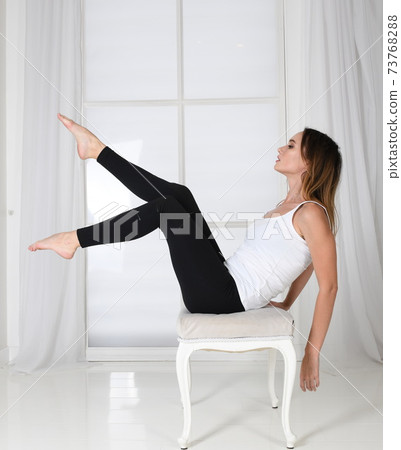Woman sits barefoot in sexy model pose with leg raised Woman sits barefoot in sexy model pose with leg raised 73768288