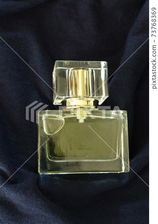 perfume or eau de toilette in square glass bottle on blue fabric background perfume or eau de toilette in square glass bottle on blue fabric background 73768369