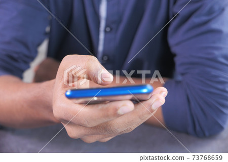 Close up of young man hand using smart phone. Close up of young man hand using smart phone. 73768659