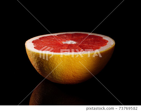 Half a grapefruit close-up on a black background. Half a grapefruit close-up on a black background. 73769582