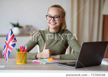 Cheerful girl with flag of Great Britain showing thumb up 73769586