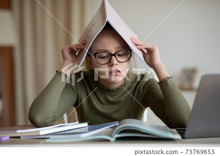 Upset blonde girl teenager doing homework at home 73769653