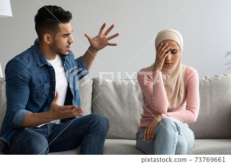 Fighting muslim man and woman sitting on couch at home 73769661
