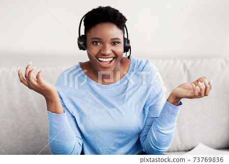 Black woman sitting, talking to camera wearing headset 73769836