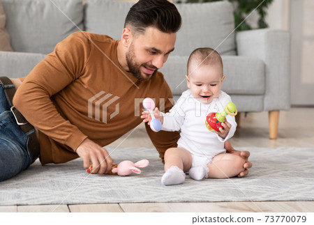 Dad Playing With Little Baby Toddler Holding Toys Sitting Indoors Dad Playing With Little Baby Toddler Holding Toys Sitting Indoors 73770079