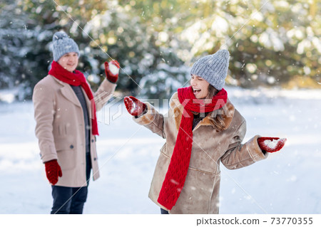 Emotional man and woman playing snowballs at city park, copy space 73770355