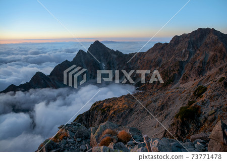 Shinshu, Northern Alps, Maehotakadake from the summit of Kitahotakadake, Okuhotakadake, sea of clouds, magic hour sky at dawn. 73771478