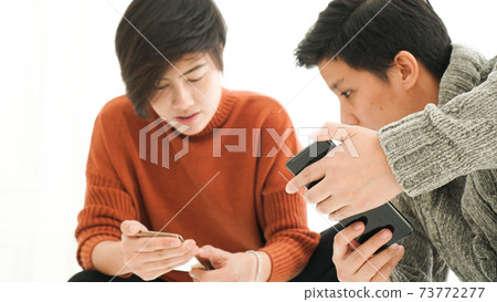 Southeast Asian friends playing smart phone togetehr in winter cloth fun 73772277