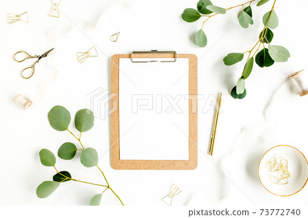 Workspace with clipboard and leaf eucalyptus on white background. Flat lay of home office desk, top view. Workspace with clipboard and leaf eucalyptus on white background. Flat lay of home office desk, top view. 73772740