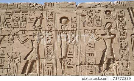 Karnak temple heiroglyphic pharaoh and god carving on stone wall 73772829
