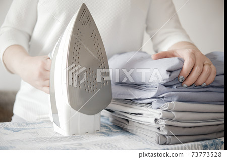 woman holding pile of bed clothes or bed linen and iron. home work concept. woman holding pile of bed clothes or bed linen and iron. home work concept. 73773528