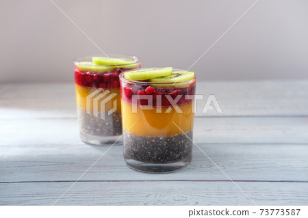 Detox and healthy superfoods breakfast concept. Vegan coconut milk chia seeds pudding with orange jelly and kiwi. Detox and healthy superfoods breakfast concept. Vegan coconut milk chia seeds pudding with orange jelly and kiwi. 73773587