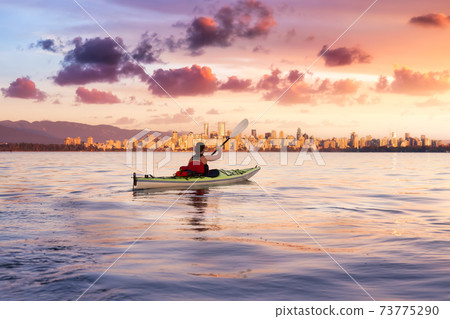 Woman on a sea kayak is paddling in the ocean Woman on a sea kayak is paddling in the ocean 73775290