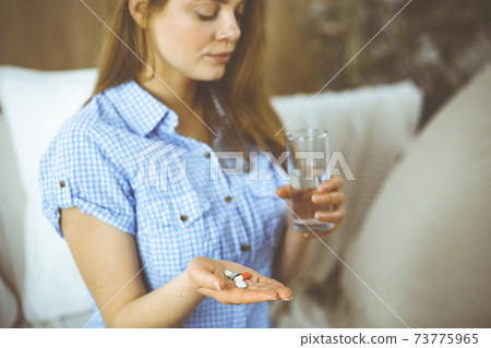 Close-up woman holding pills time to take medications, cure for headache, high blood pressure or cholesterol level remedy pain killer drugs. Medicine concept Close-up woman holding pills time to take medications, cure for headache, high blood pressure or cholesterol level remedy pain killer drugs. Medicine concept 73775965
