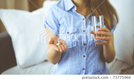 Close-up woman holding pills time to take medications, cure for headache, high blood pressure or cholesterol level remedy pain killer drugs. Medicine concept Close-up woman holding pills time to take medications, cure for headache, high blood pressure or cholesterol level remedy pain killer drugs. Medicine concept 73775966