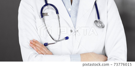 Unknown young woman doctor is standing with arms crossed in clinic. Medicine concept during Coronavirus pandemic 73776015