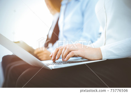 Group of diverse business people working in sunny office, close-up. Woman typing on laptop computer. Conference or training concepts Group of diverse business people working in sunny office, close-up. Woman typing on laptop computer. Conference or training concepts 73776506