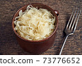 Fermented white cabbage in a pot on a table 73776652