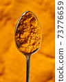 Turmeric powder on a spoon, top view 73776659