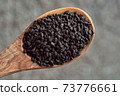 Black cumin seeds on a wooden spoon, top view 73776661