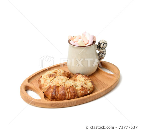 ceramic mug with cocoa and marshmallows, baked croissant on a wooden serving plate ceramic mug with cocoa and marshmallows, baked croissant on a wooden serving plate 73777537