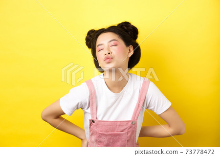 Romantic korean girl close eyes and pucker lips, waiting for sweet kiss on Valentines day, kissing lover, standing on yellow background Romantic korean girl close eyes and pucker lips, waiting for sweet kiss on Valentines day, kissing lover, standing on yellow background 73778472